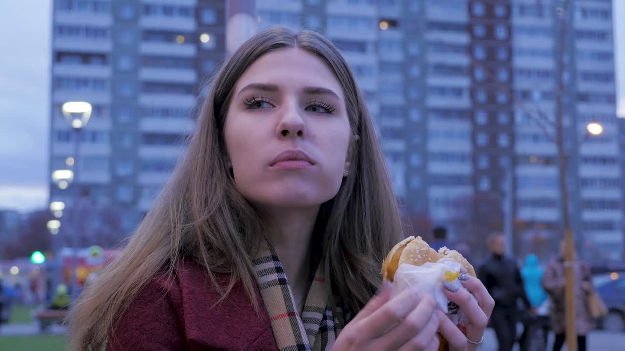 mujer comiendo una hamburguesa al aire libre