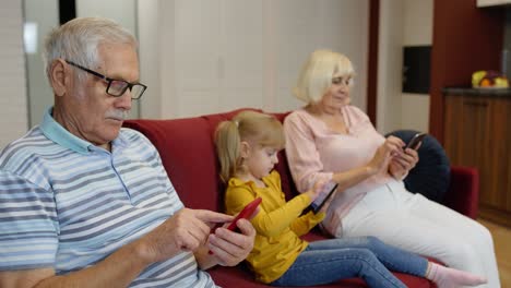 Pareja-De-Ancianos-Abuelos-Con-Nieta-Niña-Usando-Tableta-Digital,-Teléfono-Móvil