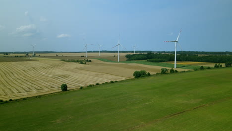 energy producing wind turbines in green fields of zwartowo pomerania, poland, aerial panning shot