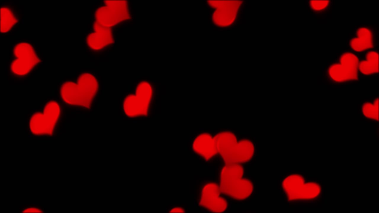 A dense shower of soft, out-of-focus red heart-shaped bokeh lights falls against a black screen. For Valentine's Day or weddings