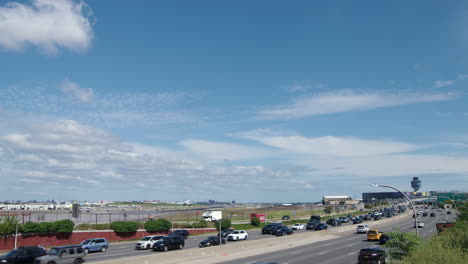 clear summer day with plane landing on runway at laguardia airport with highway traffic in foreground