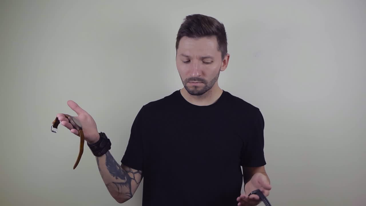 매력적인 문신 한 남자가 기계 시계를 들고 다른 손으로 스마트 시계를 비교하는 팔을 들어 올리는 느린 동작 영상