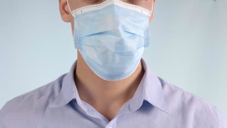 extreme closeup of man putting disposable face mask over mouth and nose