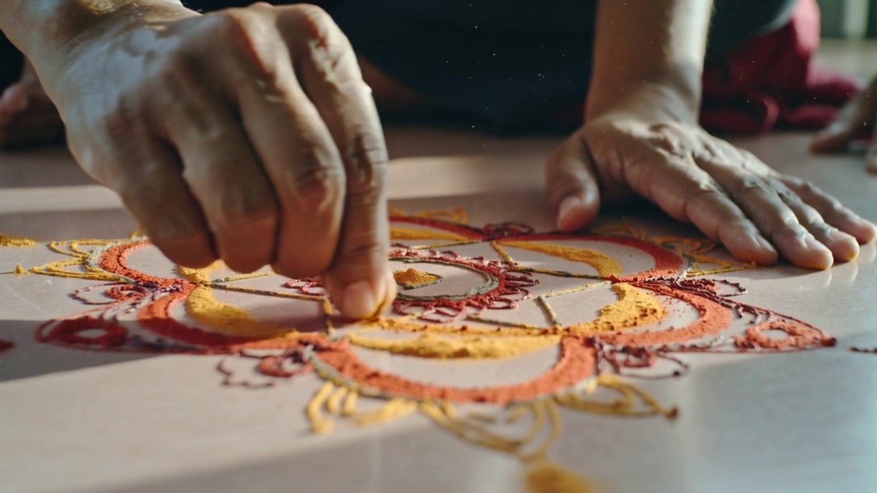 Posizionando sabbia colorata, mani d'artista formano un mandala sul pavimento di casa per decorazione.