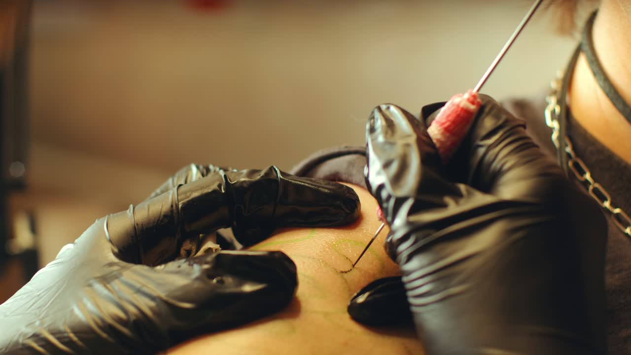 Gloved Hands of Tattoo Artist Applying Ink into Skin with Needle