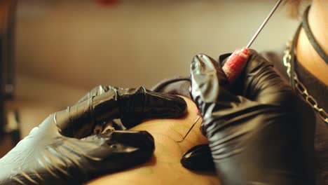 gloved hands of tattoo artist applying ink into skin with needle