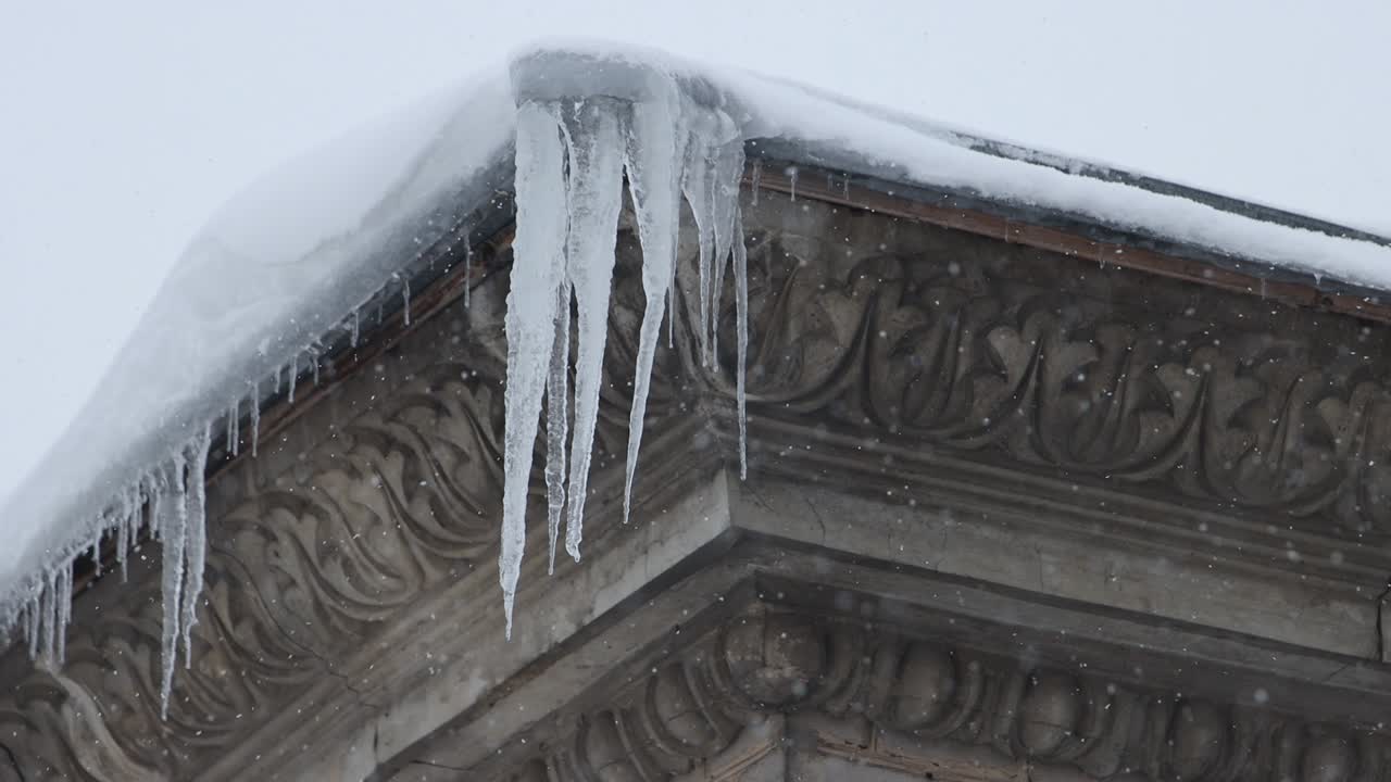 icicles hang on the edge of the house during a snowfall