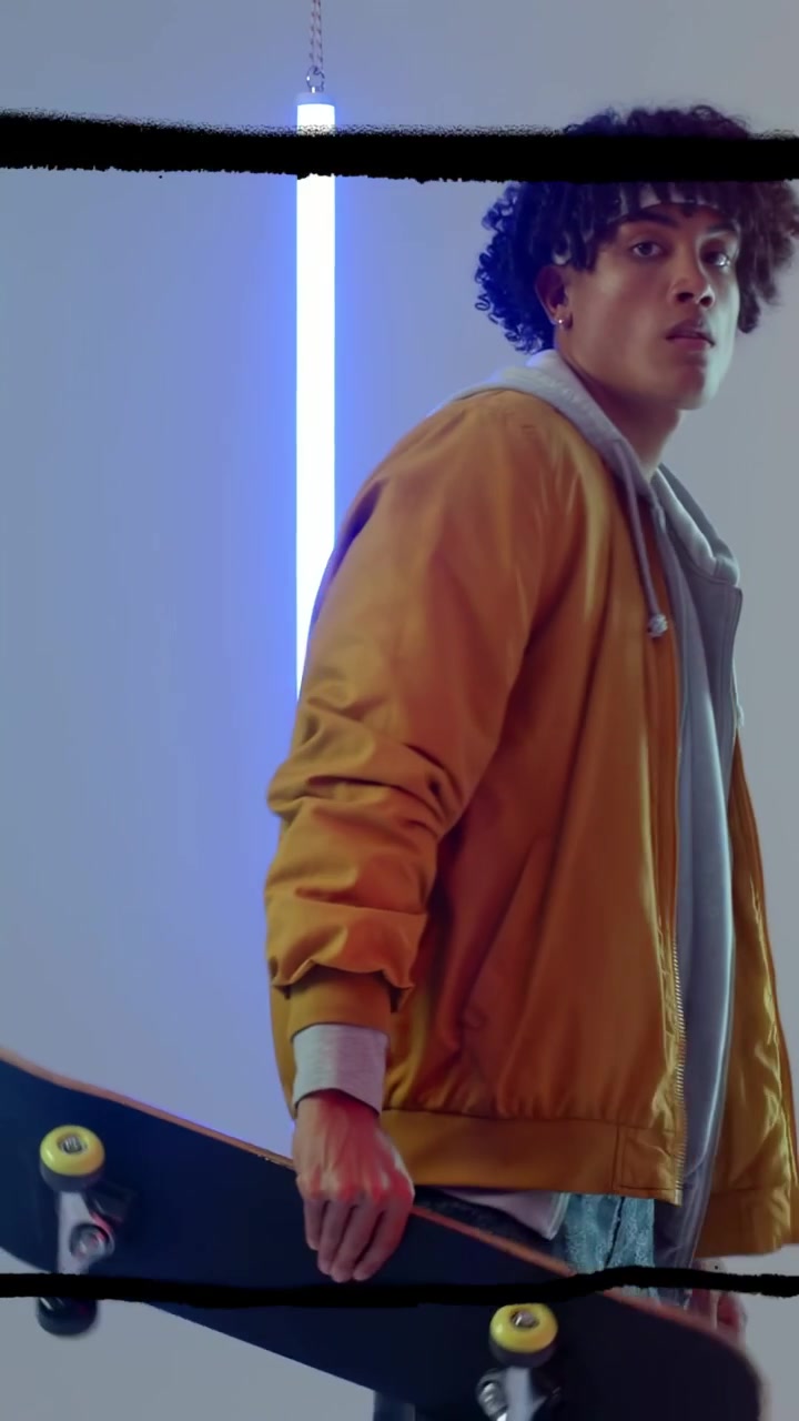 Vertikal video: Skater tråkker på brettet, løfter det oppreist, poserer stilig med neon-svarte streker som krysser