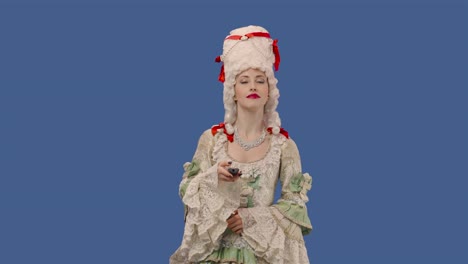 portrait of courtier lady in white vintage dress and wig watching tv and changing channels using remote. young woman posing in studio with blue screen background. close up. slow motion ready 59.94fps