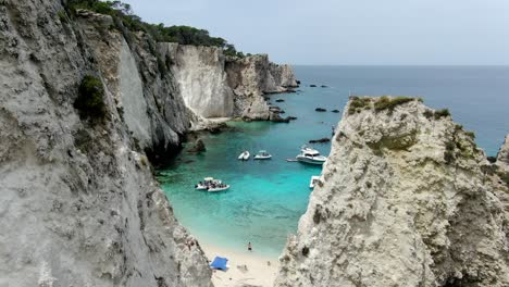 Drone-captures-breathtaking-view-of-the-Adriatic-Sea's-gorgeous,-crystal-clear-waves-from-between-two-rocky-hills-on-the-Italian-island-of-Tremiti