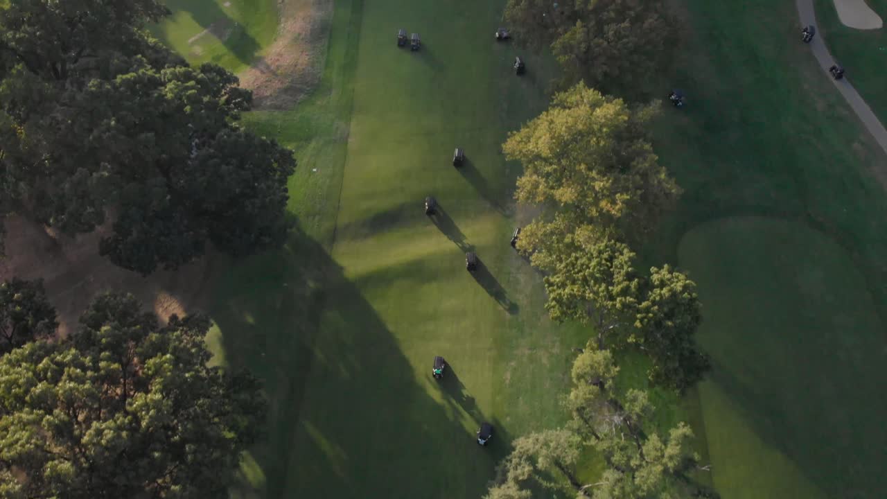 4K Drone shot over group of gold carts driving on a golf course