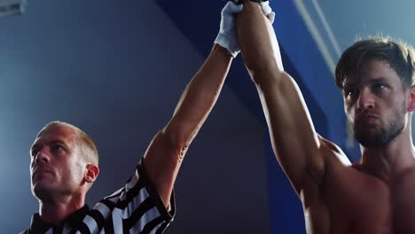 boxeador sosteniendo la mano del ganador después de anunciar la victoria