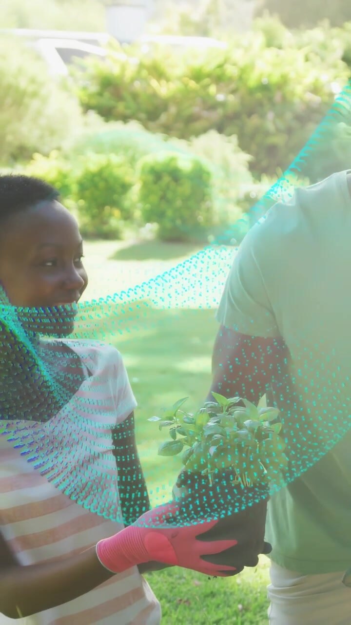Vertical video: Man handing plant to woman teaching gardening while teal sweeping over hands
