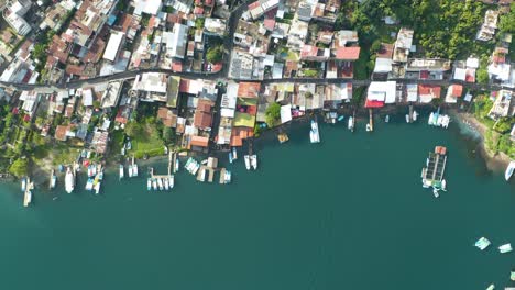 drone de arriba hacia abajo panorámica cenital a través del lago atlán costa de guatemala casas y barcos