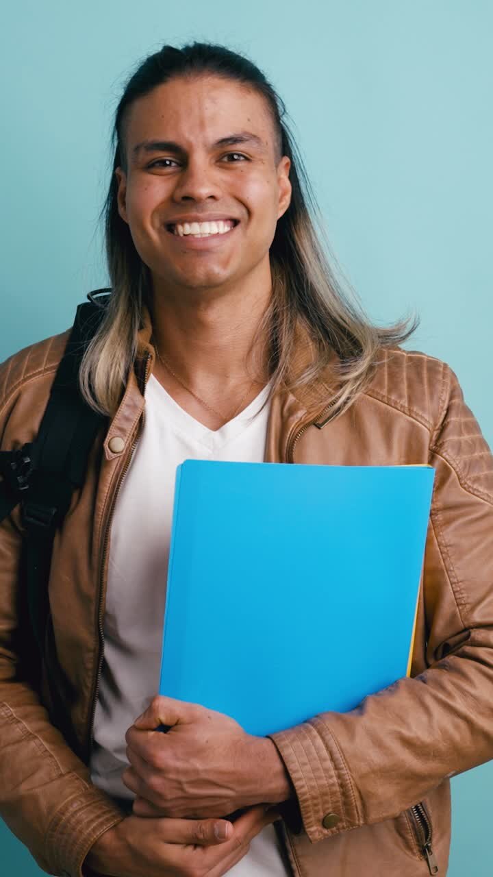 Studente felice che tiene una cartella e sorride alla fotocamera