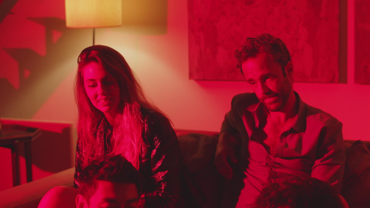 집 파티에서 은 빛으로 어두운 방에 앉아있는 친구들