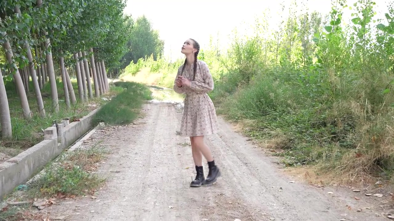 Una donna passeggia tranquillamente lungo un sentiero sterrato panoramico, circondata da bellissimi alberi e vegetazione.