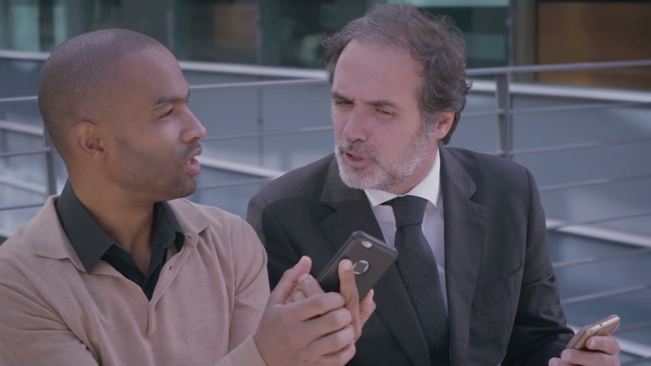 사무실 건물 근처 에서 대화 하는 스마트폰 을 가진 자신감 있는 관리자 들