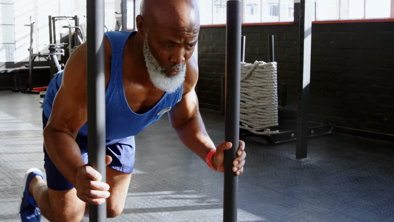 Senior man pushing weight sled in the fitness studio 4k