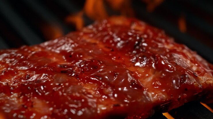 Marinated Ribs Barbecuing On The Charcoal Grill Among Bursting Flames, BBQ in Macro and Slow Motion