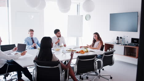 Hombres-Y-Mujeres-De-Negocios-Reunidos-En-Una-Moderna-Sala-De-Juntas-Durante-Un-Almuerzo-De-Trabajo-Filmado-En-Cámara-Lenta.