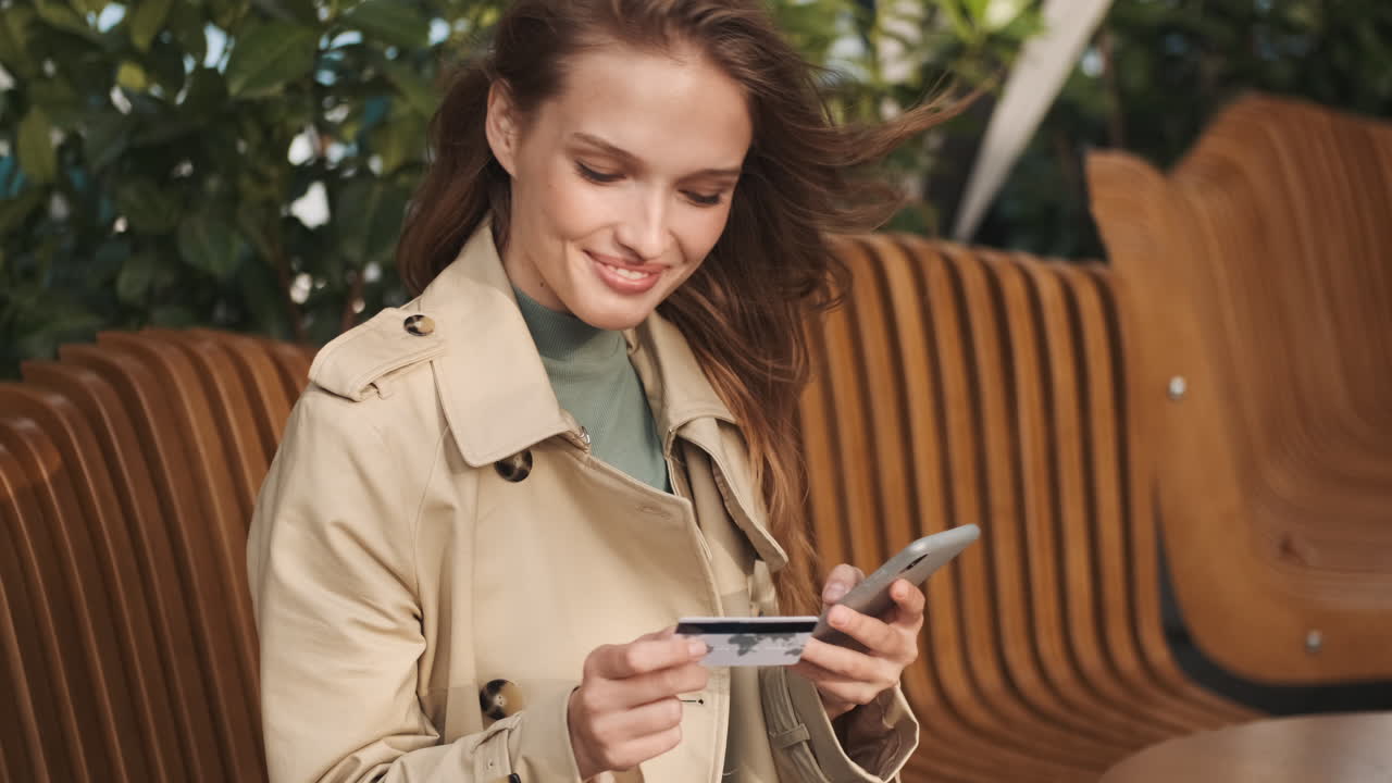 кавказская студентка делает онлайн-покупки на смартфоне на открытом воздухе.