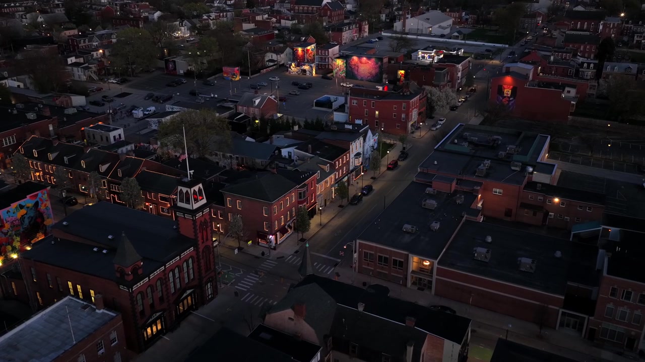 Aerial view of downtown York, Pennsylvania at dusk with historic brick buildings, illuminated streets and landmark tower with American flag. Scenic evening city center scene in USA.
