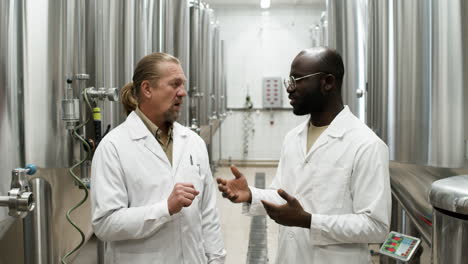 twee mannen praten in een fabriek.