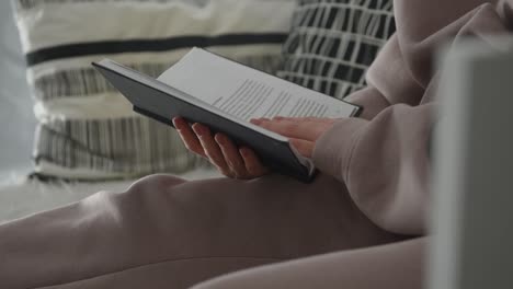 La-Mujer-Está-Leyendo-Un-Libro-En-El-Sofá,-Pasando-Páginas,-Ambiente-Hogareño-Acogedor