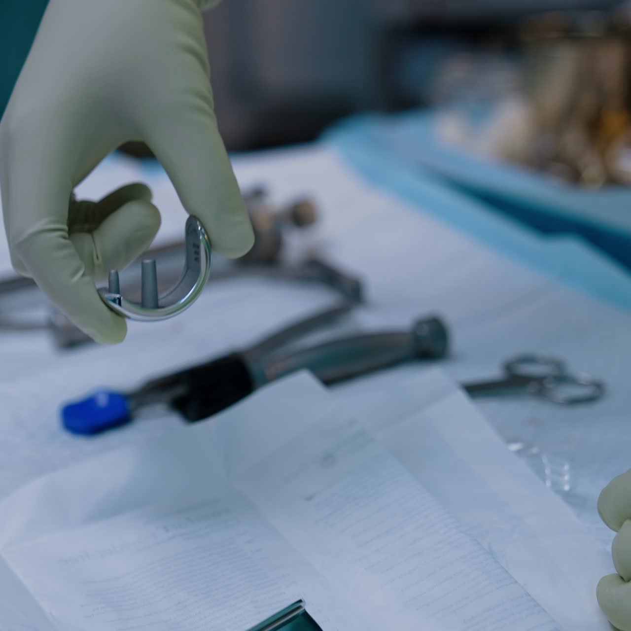 Orthopedic instruments and materials on the table. Doctor's gloved hand takes a detail demonstrating it. Close up