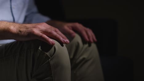 Close-Up-Of-Anxious-Depressed-Man-Fidgeting-Sitting-In-Darkness-With-Low-Key-Lighting