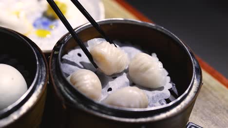 chopsticks picking shrimp dumplings from a steamer