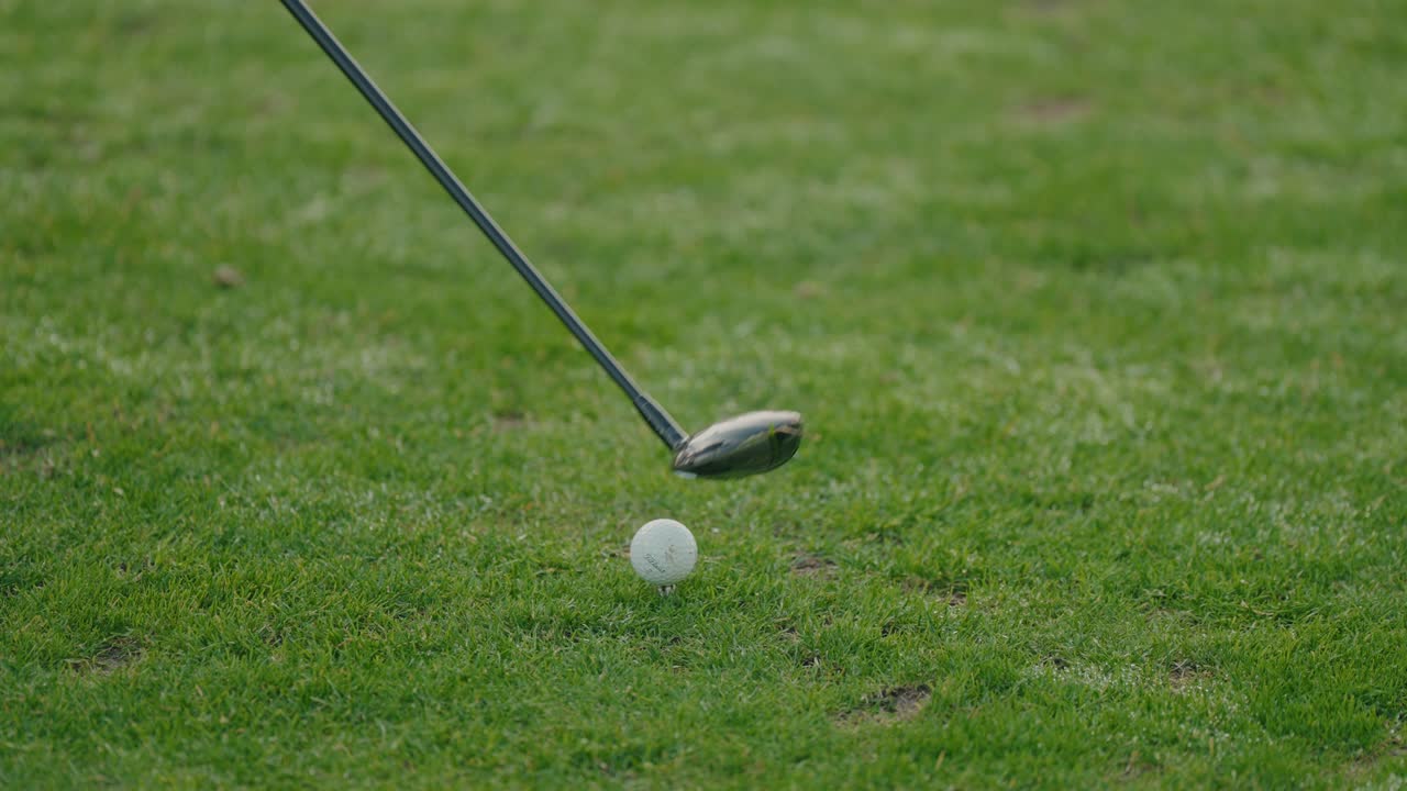 primer plano de un palo de golf golpeando la bola en el momento del impacto sobre la hierba