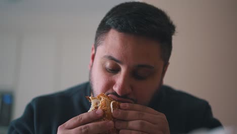 Young-hungy-man-eats-a-hamburger-with-his-mouth-wide-open