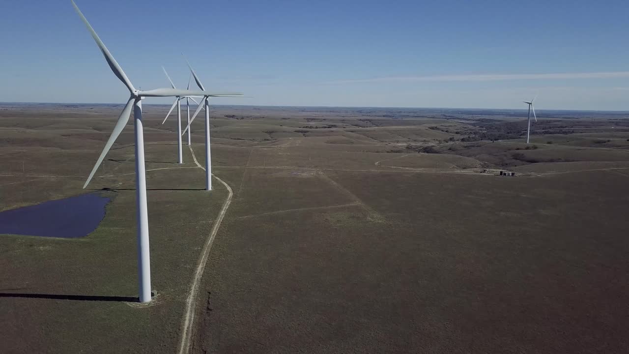 Aerial drone footage of windmills during summer over farm fields in Kansas, United States