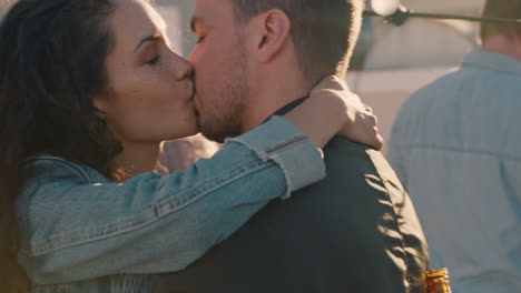 pareja feliz besándose disfrutando de una fiesta en la azotea bailando a música animada compartiendo una relación romántica en una reunión social diversa al atardecer