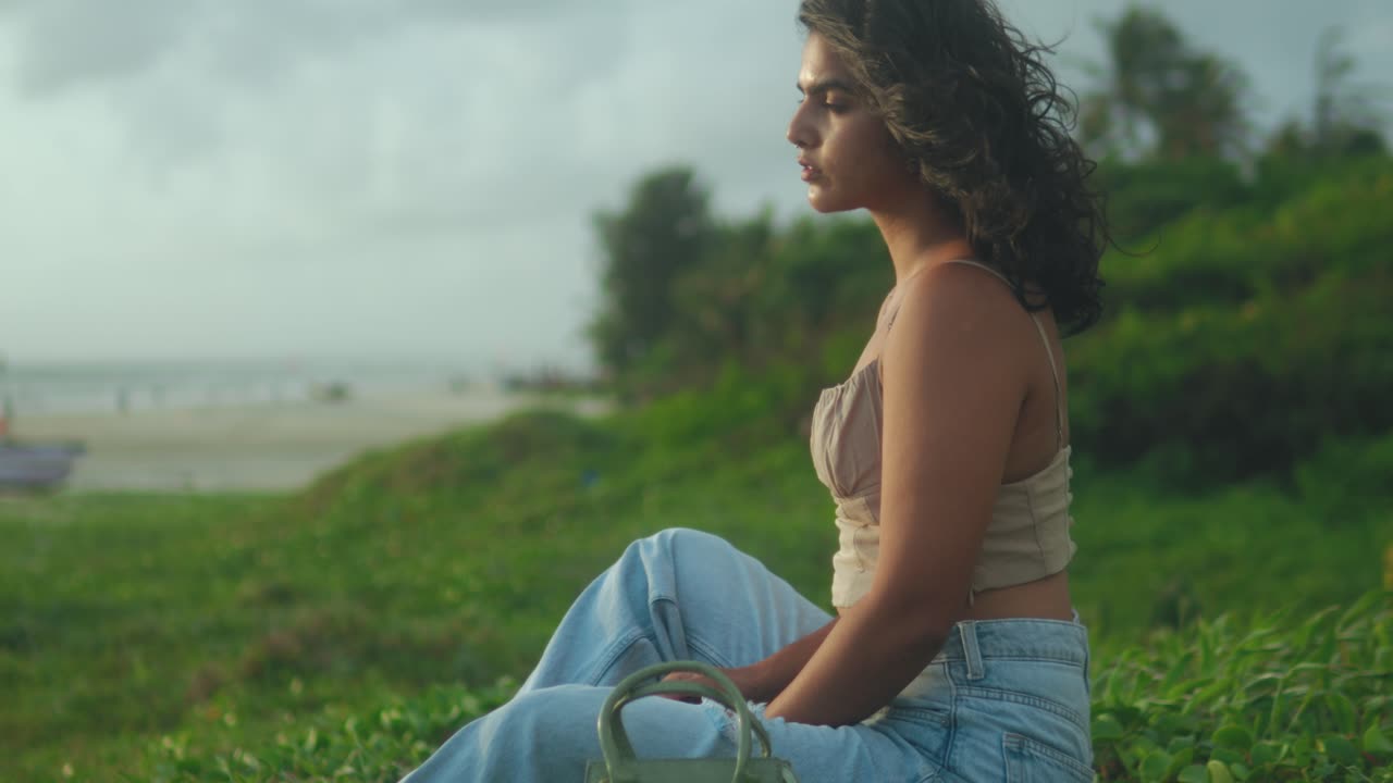 Young Woman Sitting on Coastal Cliff Looking Toward the Sea