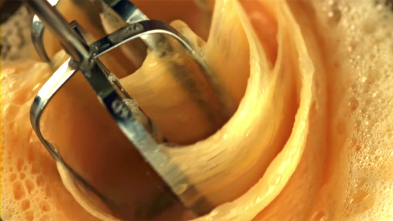 Close-up of Electric Mixer Whisking Eggs into a Foamy Mixture