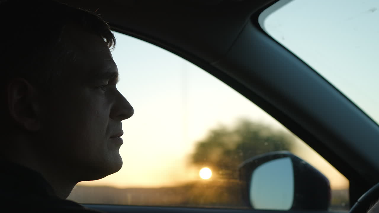 Middle-aged man driving sleek automobile during golden hour, experiencing tranquil moment while navigating a highway with confidential demeanor and focused mindset
