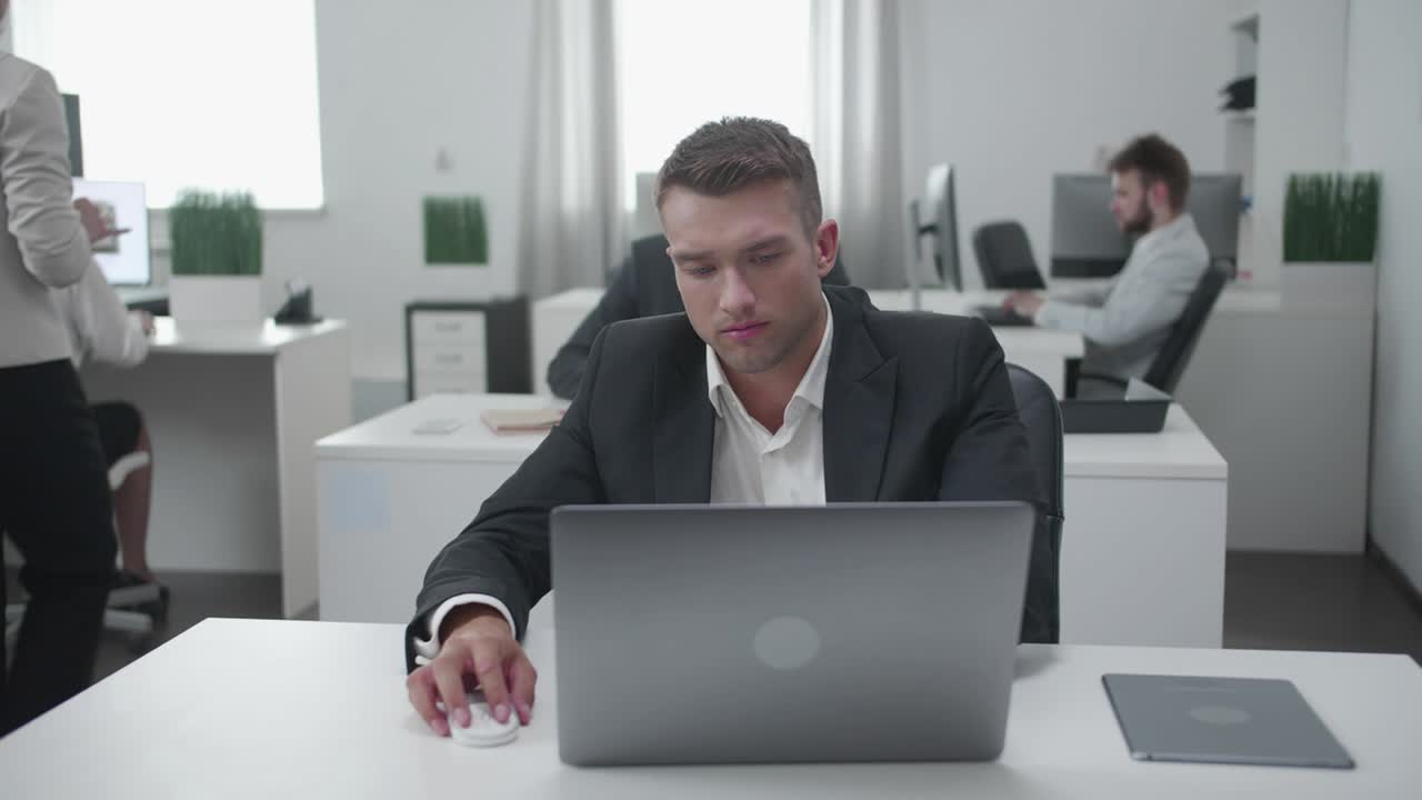 Обычный день в офисе, мужчина работает за ноутбуком