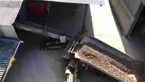 potatoes being loaded onto a grader aerial view and then pan backwards across the farm yard