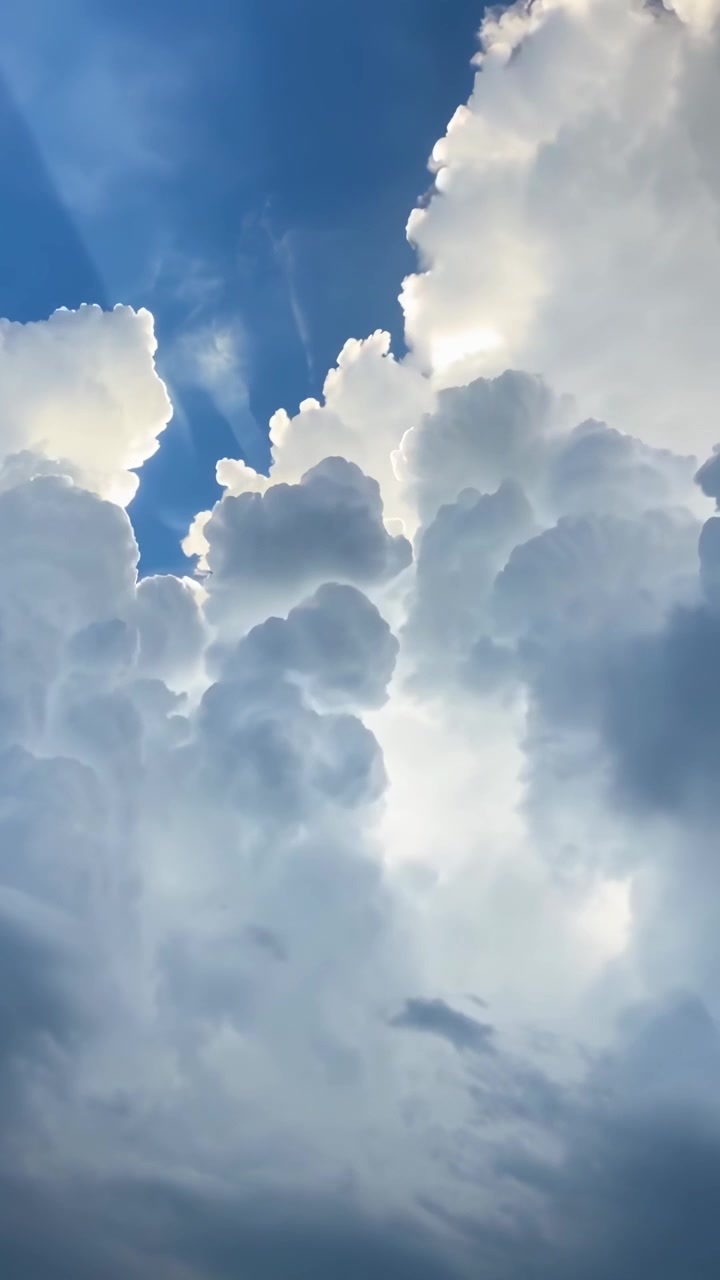 Sunlight Breaking Through Majestic White Clouds in Blue Sky