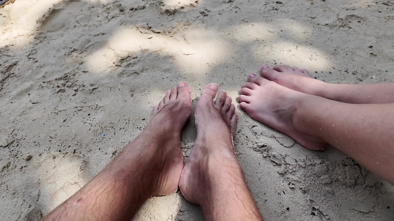 Young couple on the beach looking down at their feet