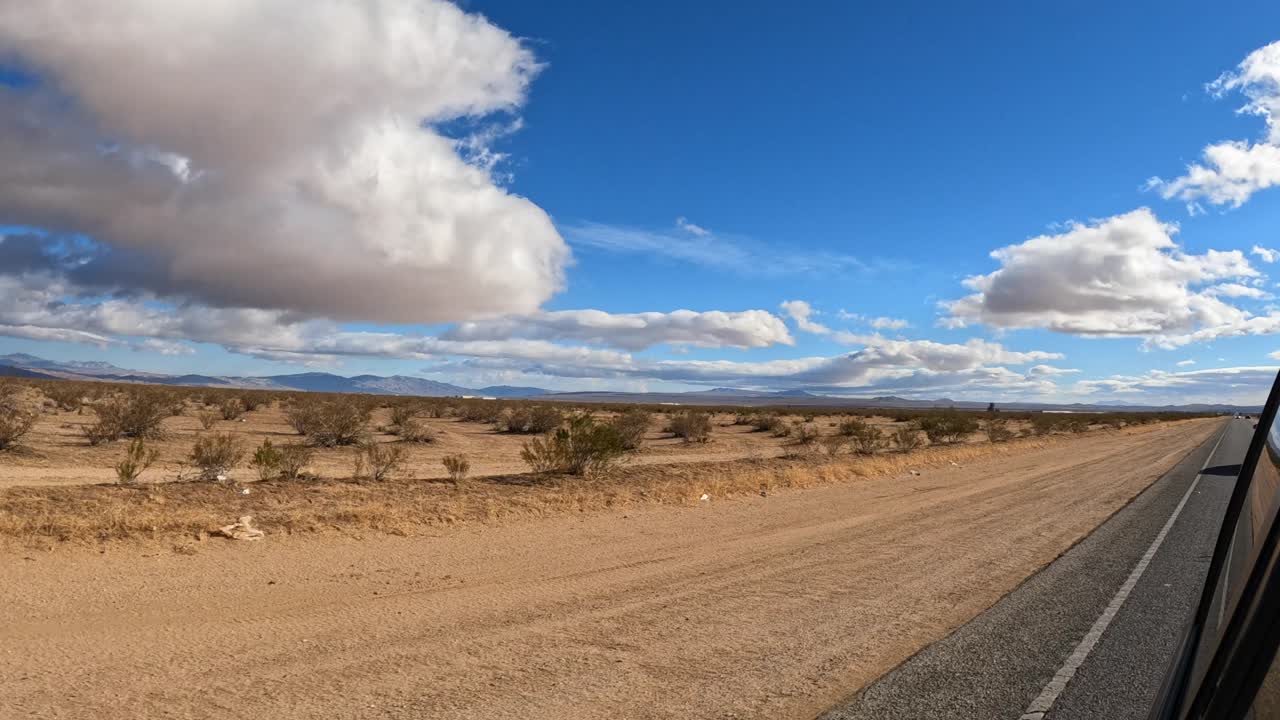 el desierto de mojave visto desde el espejo retrovisor lateral del camión en un día con nubes sobre el páramo yermo