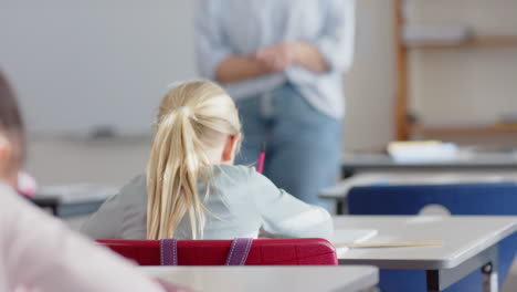 In school, girl raising hand with pencil, paying attention to female teacher