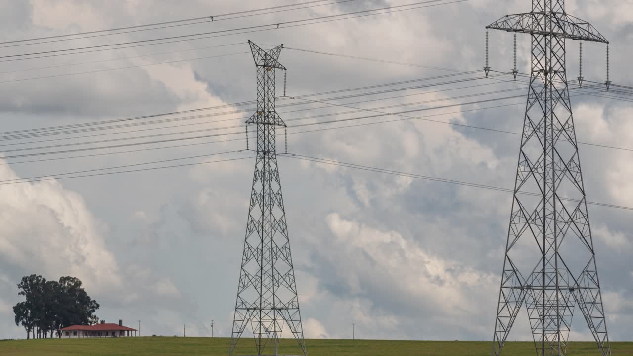 Electricity transmission towers in a rural field, timelapse with movement of clouds