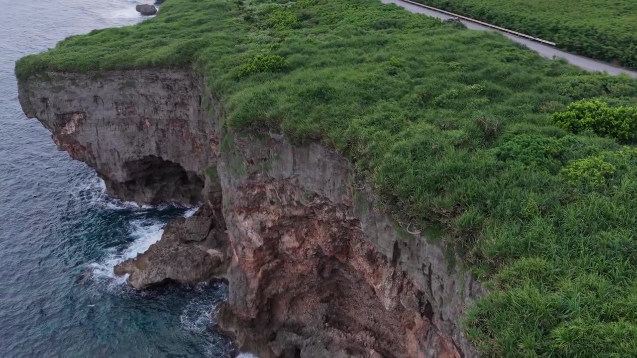 Horizontal aerial footage dollying forward along the rugged sea cliffs of Muiga Cliffs near the Wind Energy Windmills, Miyakojima, Okinawa, Japan