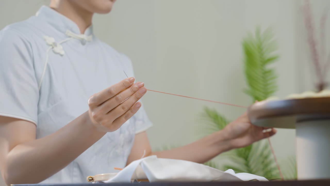 Artigianato tradizionale: giovane donna creativa che ricama abilmente un disegno colorato, la mano della ragazza è nel telaio da ricamo. Lavoro di ricamo artigianale mentre è seduta al posto di lavoro.