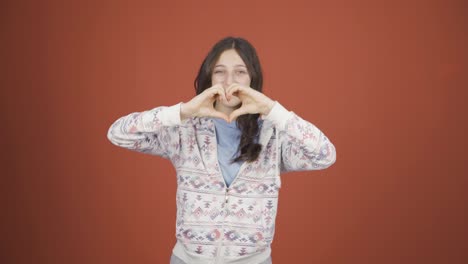 young woman making heart sign at camera.