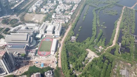 vista aérea de una ciudad con una escuela, un estadio y un bosque de manglares
